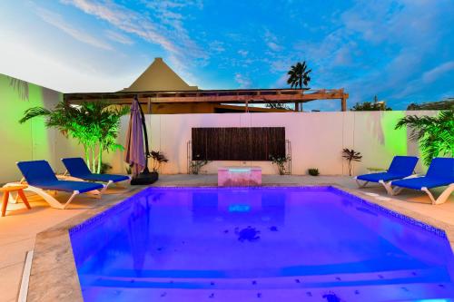 a swimming pool with blue chairs and a table at Boutique Hotel Swiss Paradise Aruba Villas and Suites in Palm-Eagle Beach