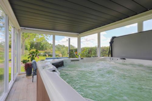 une grande baignoire jacuzzi dans une chambre avec fenêtres dans l'établissement Chalet Pondok Indah, à Plouégat-Moysan