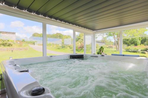 a jacuzzi tub in a room with windows at Chalet Pondok Indah in Plouégat-Moysan