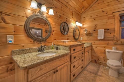 a log cabin bathroom with a sink and a toilet at Sassafras Lodge - Cabin in North GA - Pet Friendly - Hot Tub, Fireplace, Mountain Views, Gas Griddle, Outdoor Fire Pit, Shuffleb in Mineral Bluff