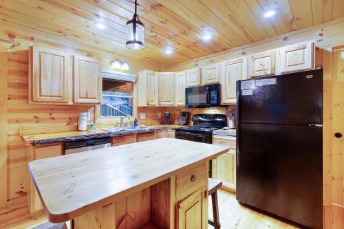 a kitchen with a black refrigerator and wooden cabinets at Storybook Hideaway - Pet Friendly - Toccoa River in Blue Ridge