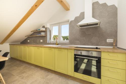 a kitchen with yellow cabinets and a stove at Apartments Laura in Mali Lošinj