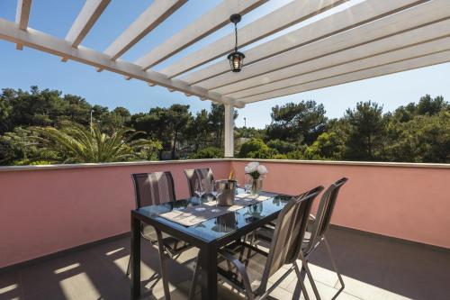 a table and chairs on a patio with a pergola at Apartments Laura in Mali Lošinj