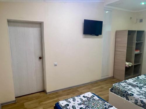 a room with two beds and a television on the wall at Гостевой дом Сафар in Kapchagay