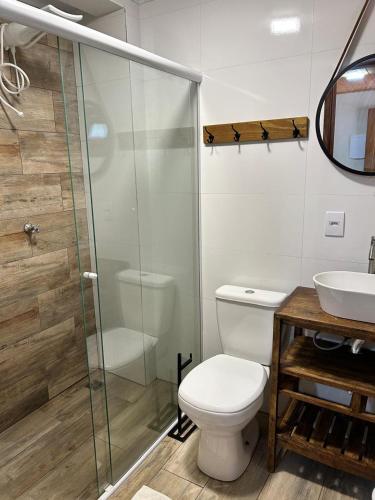 a bathroom with a toilet and a glass shower at Pousada Tribo Do Sol in Ubatuba