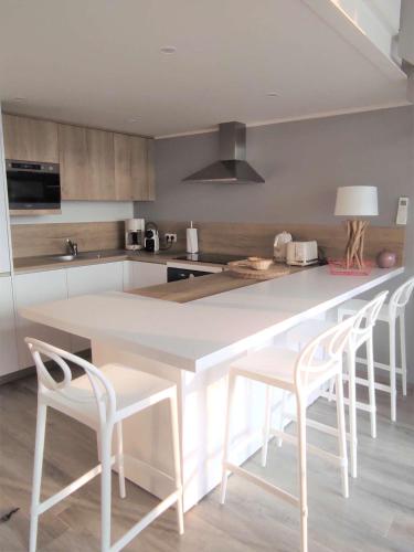 une cuisine avec un comptoir et des tabourets blancs dans l'établissement Appartement 2 pièces duplex Hotel Club Porticcio, à Porticcio