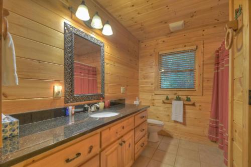 ein Badezimmer mit Waschbecken und Spiegel in einer Blockhütte in der Unterkunft Stoney Creek Retreat - North Georgia Mountains in Cherry Log