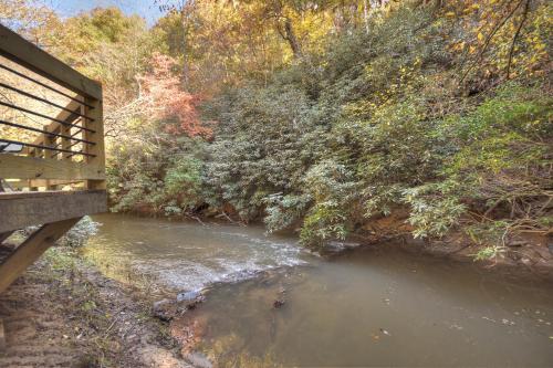 a bench sitting next to a river next to a forest at Happy Trout Hideaway - Creek Views Of Hot House Creek, Hot Tub, Outdoor Fire Pit, Cozy Atmosphere - Mineral Bluff, GA in Mineral Bluff