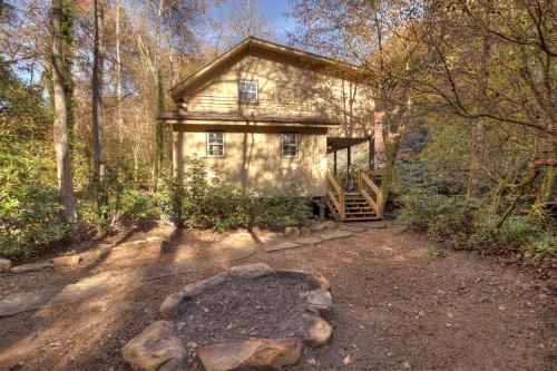a house in the middle of a forest at Happy Trout Hideaway - Creek Views Of Hot House Creek, Hot Tub, Outdoor Fire Pit, Cozy Atmosphere - Mineral Bluff, GA in Mineral Bluff