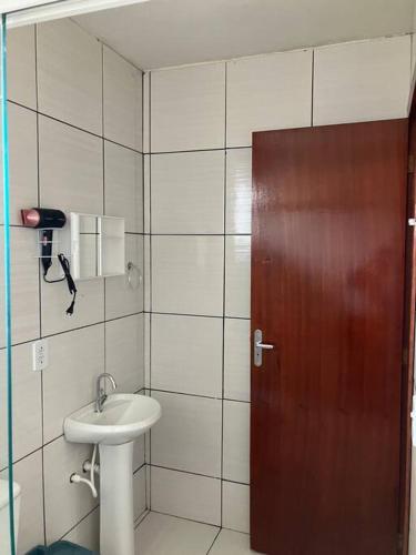 a bathroom with a sink and a wooden door at Geminado da mada casa 3 in Penha