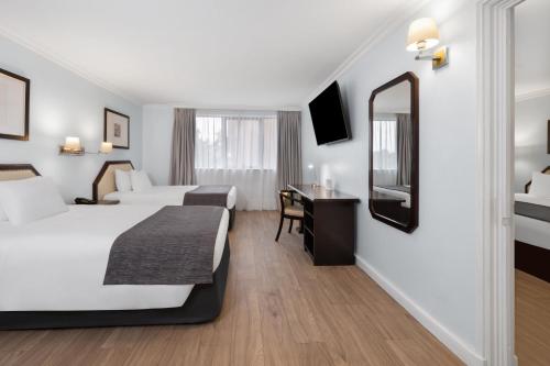 a hotel room with two beds and a mirror at Wyndham Garden Santiago Kennedy in Santiago