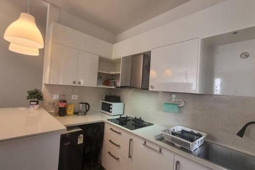 KammasandraにあるDeeSam's Cozy Flat in Sarjapurの白いキャビネットとコンロ付きオーブンを備えたキッチン