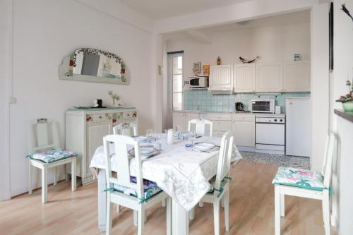 une cuisine avec une table et des chaises et une cuisine avec des armoires blanches dans l'établissement Appartement a deux pas de la plage des Sables d Olonne 4 personnes, à Les Sables-dʼOlonne