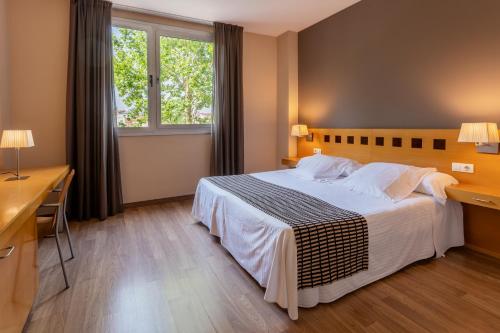 1 dormitorio con cama, escritorio y ventana en Ponient Vila Centric by PortAventura World en Vilaseca