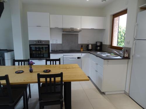 une cuisine avec des armoires blanches et une table en bois dans l'établissement Le Nid Douillet des prés, à Grézieu-la-Varenne