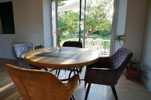 - une table et des chaises en bois dans une chambre avec fenêtre dans l'établissement La Longère, à La Menitré