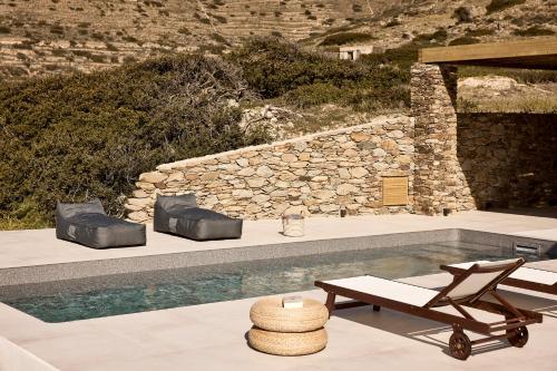 a swimming pool with two lounge chairs and a table at Thea Luxury Villas Ios in Plakotos