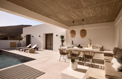 a patio with a table and chairs and a pool at Thea Luxury Villas Ios in Plakotos