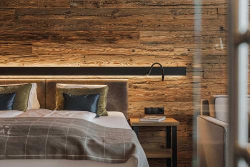 a bedroom with a bed and a wooden wall at Sportresidenz Zillertal - 4 Sterne Superior in Uderns