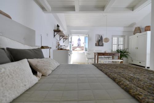 a bedroom with a large bed with white walls at Boutique Guesthouse NA VALU in Krk