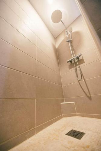 une douche avec pommeau de douche dans une salle de bain dans l'établissement La Bonbonnière de Saint Maclou, à Rouen