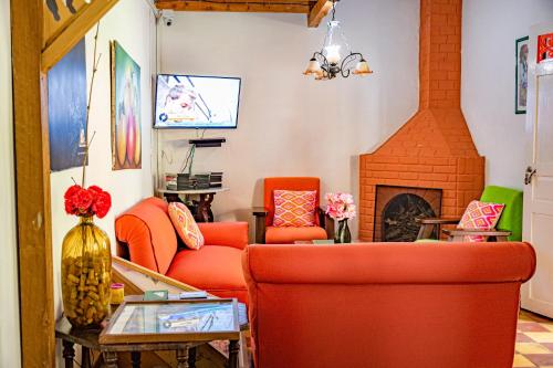 a living room with orange chairs and a fireplace at Kantarrana Casa de Campo in Jardin