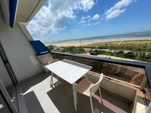 un balcon avec une table et des chaises et une vue sur la plage dans l'établissement Studio Face Mer, à Saint-Jean-de-Monts