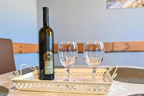 a bottle of wine and two wine glasses on a tray at House Silvijo in Pag