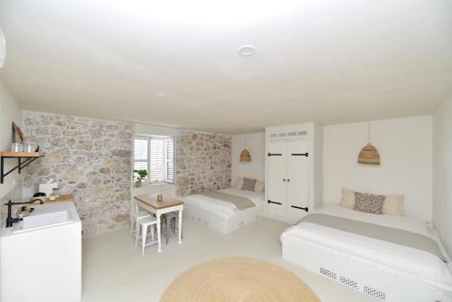 a white room with two beds and a table at Boutique Guesthouse NA VALU in Krk