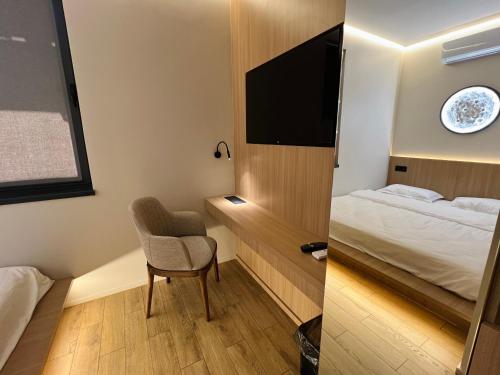 a room with a bed and a chair and a television at ALEM Hotel in Almaty