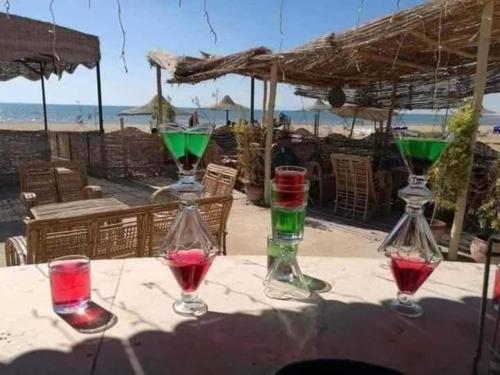 four wine glasses sitting on a table near the beach at شاليه قرية بلولاجون راس سدر - 3 غرف و2 حمام in Ras Sedr