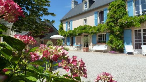 une maison avec des fleurs roses devant elle dans l'établissement Les Volets Bleus, à Saint-Martin-des-Entrées
