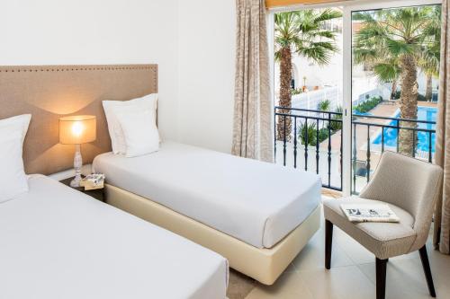 une chambre d'hôtel avec deux lits et un balcon dans l'établissement The Village – Praia D’El Rey Golf & Beach Resort, à Casal da Lagoa Seca