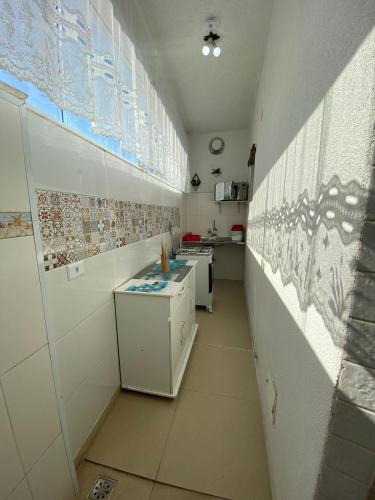 a small kitchen with white appliances and tiles on the wall at Suítes Sol do Guarujá in Guarujá