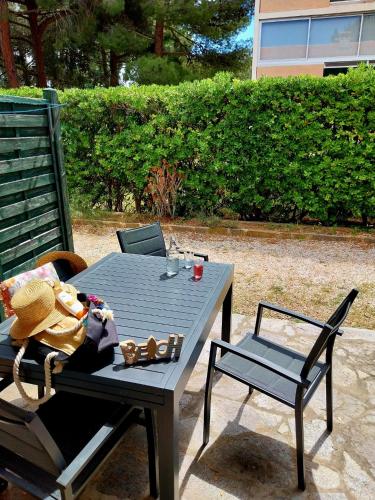 une table et des chaises assises sur une terrasse dans l'établissement Prélude Beach, à Bormes-les-Mimosas