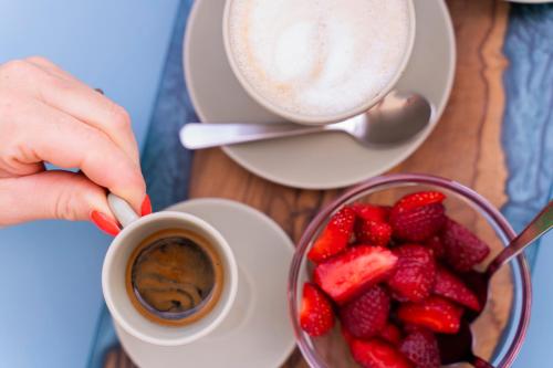 a person holding a cup of coffee and a bowl of strawberries at Greenlove in Agerola