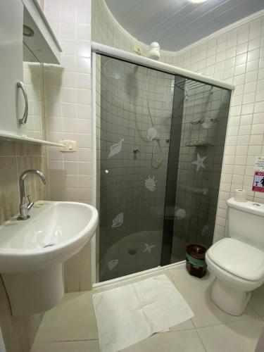 a bathroom with a shower and a sink and a toilet at Suítes Sol do Guarujá in Guarujá