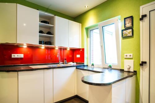 a kitchen with red and green walls and white cabinets at W20 I Gruppen I 7 Zimmer für 9 I 2 Bäder I Garten I Netflix Smart TV I Premium in Mettingen