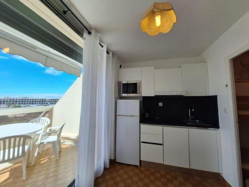 Il dispose d'un balcon et d'une cuisine avec des placards blancs et une table. dans l'établissement Studio Héliopolis L1 -Vue mer - 4 personnes, au Cap d'Agde