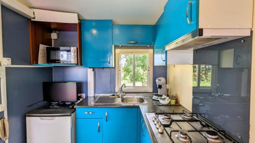 una cucina blu con lavandino e piano cottura di Cottage flottant Terrasse Nature près Dijon a Ouges