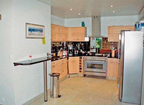 une cuisine avec des armoires en bois et un réfrigérateur en acier inoxydable dans l'établissement Castorina, à Benerville-sur-Mer