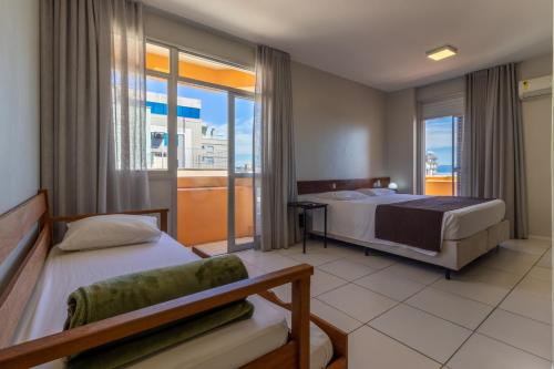 a hotel room with two beds and a balcony at Rio Branco Hotel in Florian&oacute;polis