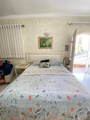 a bedroom with a large bed with a floral bedspread at Suítes Sol do Guarujá in Guarujá