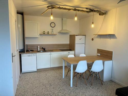 une cuisine avec une table en bois et des appareils électroménagers blancs dans l'établissement Le Saint-Ange, appartement accès direct à la plage, au Barcarès