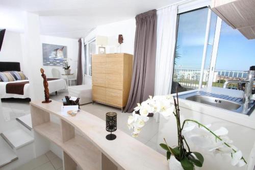 a white living room with a large window at Bleu Mer Duplex & Suites in Saint-Cyprien