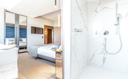 a hotel room with a bed and a shower at Das Ahlbeck Hotel & SPA in Ahlbeck