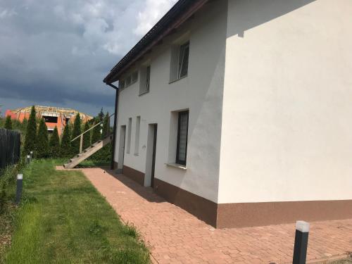 a white building with a brick sidewalk next to it at Tanie Pokoje Kajetany in Kajetany