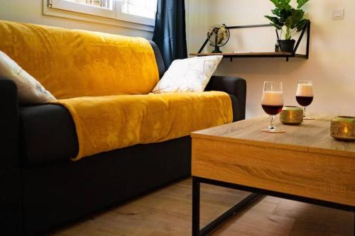 un canapé jaune avec deux verres de vin sur une table dans l'établissement Le Soleil Montilien, à Montélimar