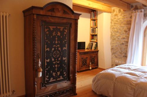 a bedroom with a large wooden cabinet next to a bed at Ronchet Baita Vanoi Trentino in Ronco