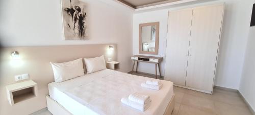 a white bedroom with a large white bed with two towels at Bella Mare Luxury Apartments in Kalamaki Heraklion